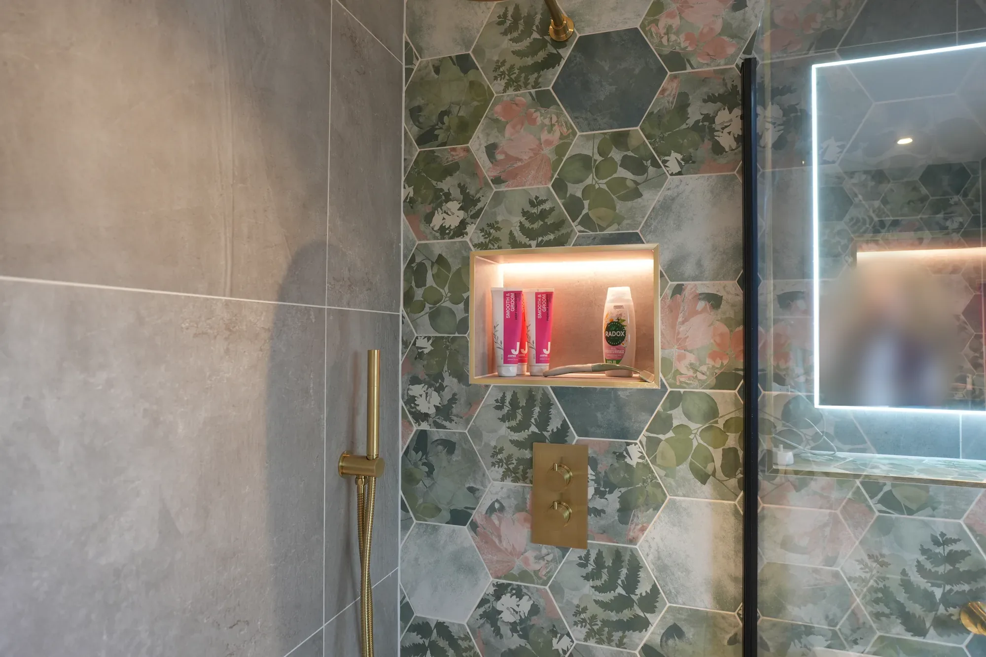 Shower with brass fittings and lit niche at our Brentwood project.