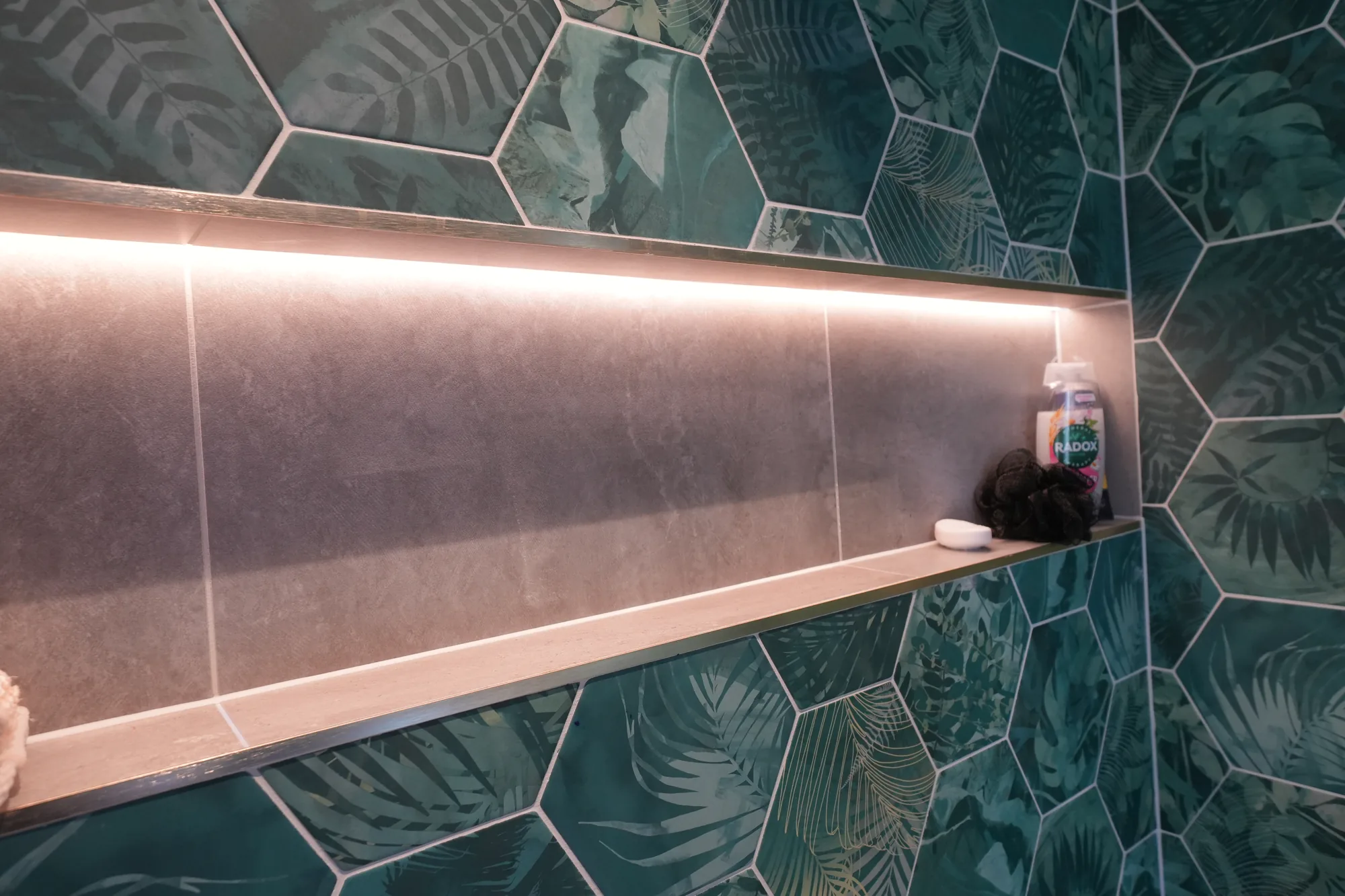 Green feature tiling with lit niche in the bathroom of our Brentwood project.
