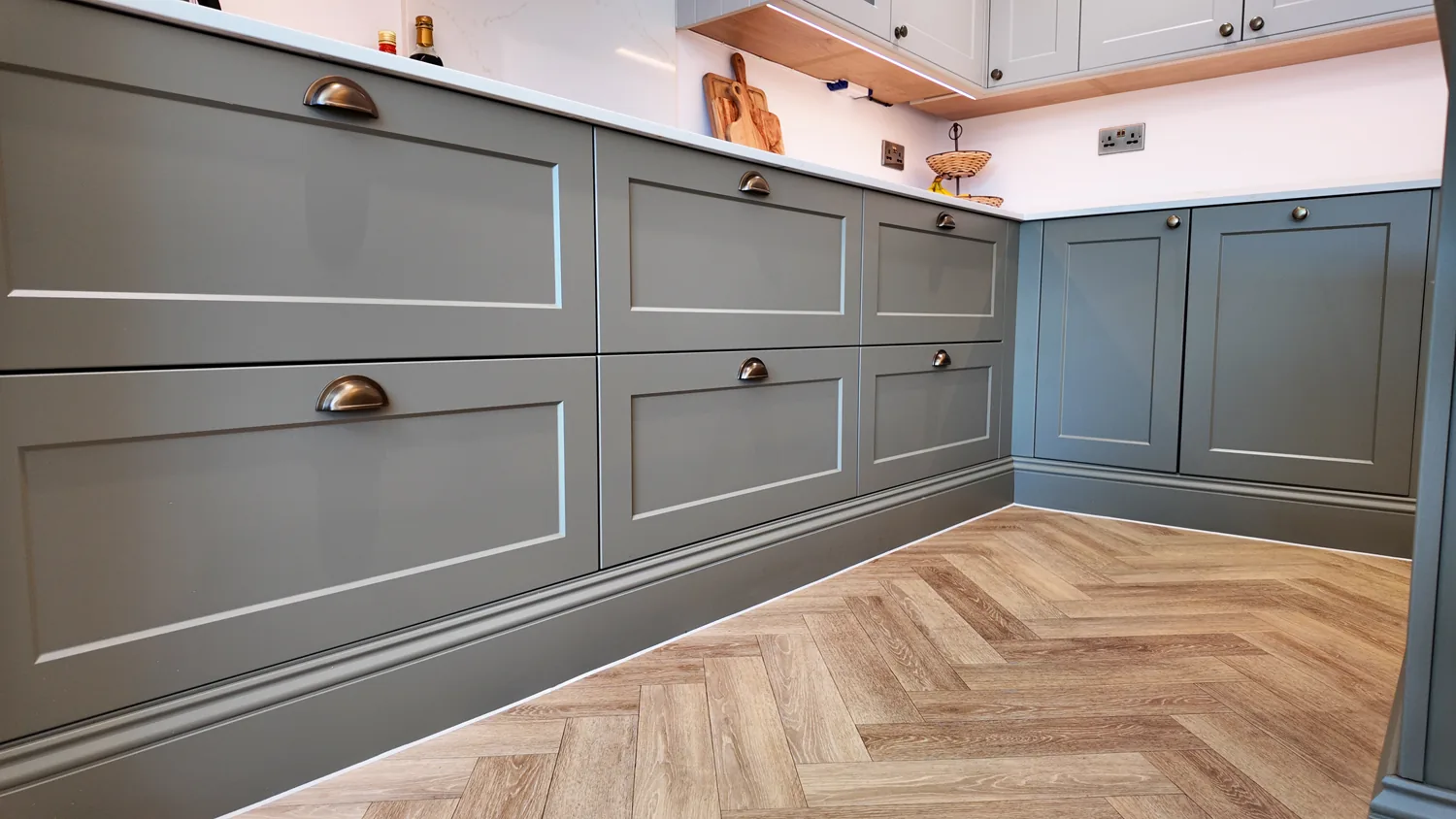 Sage green shaker cabinetry and herringbone flooring in the new Billericay kitchen.