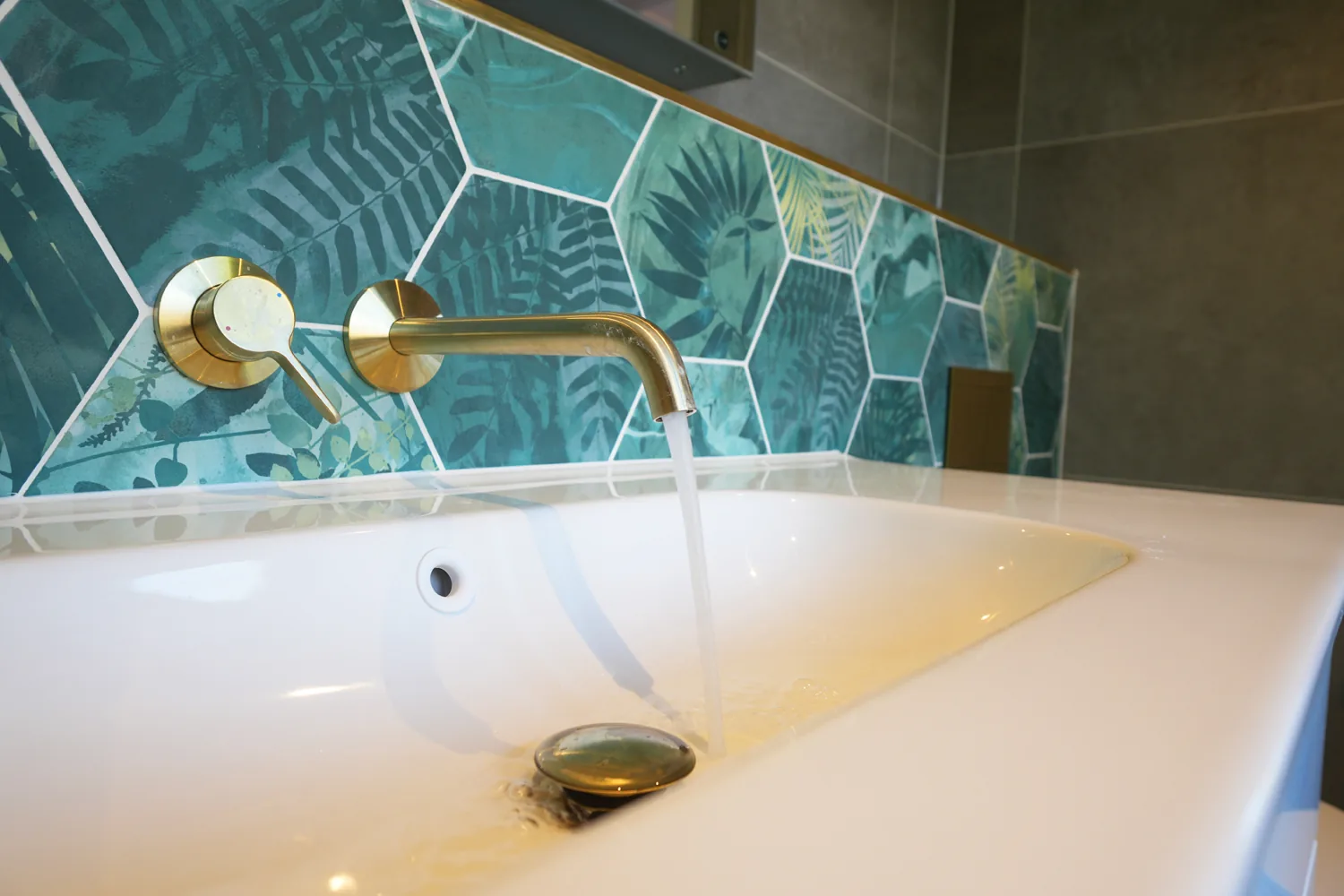 Wall mounted brass tap running into the vanity basin of the green tiled Brentwood bathroom.