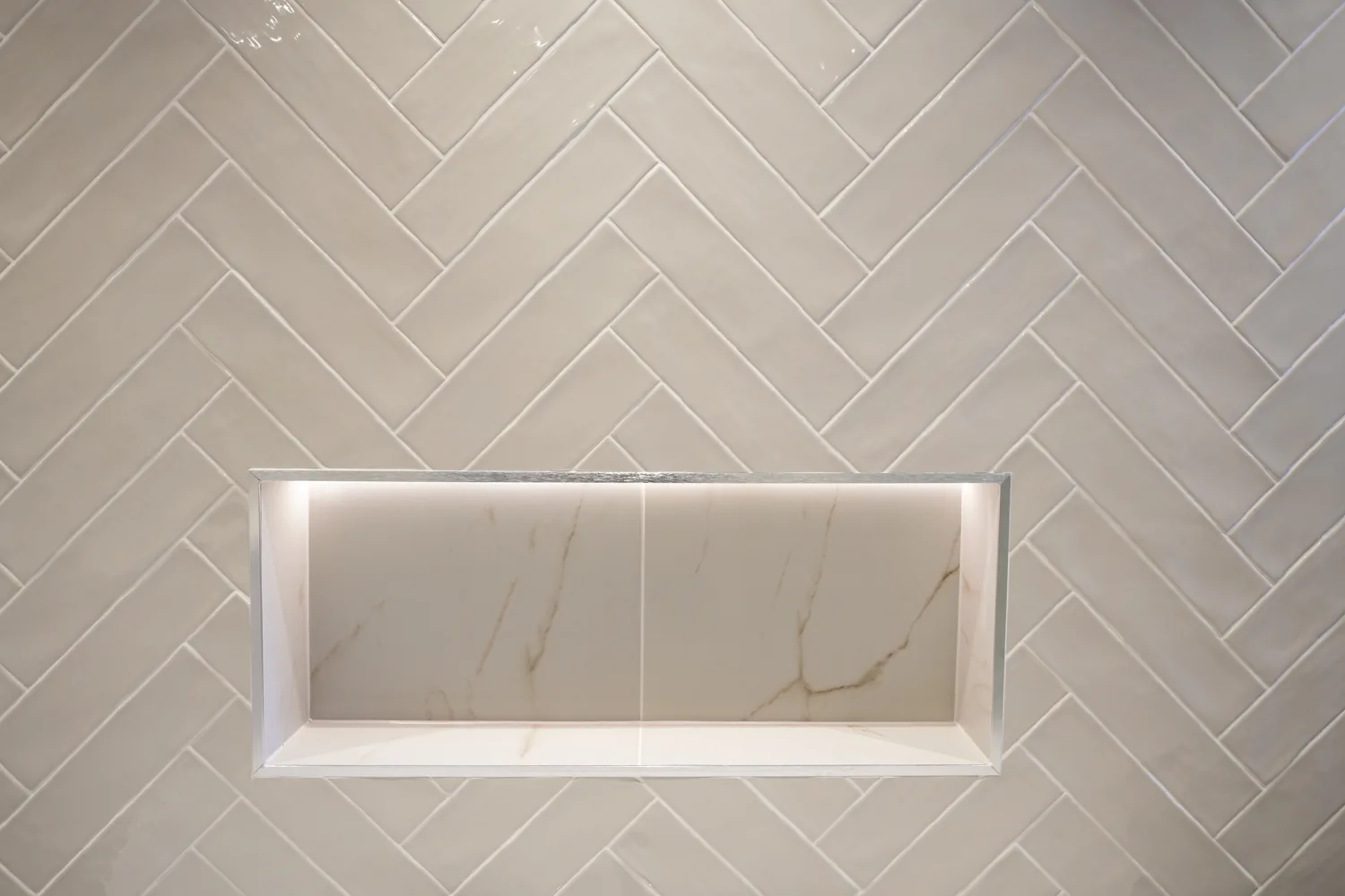 Recessed lit storage niche set into herringbone tiling in the Brentwood main bathroom.