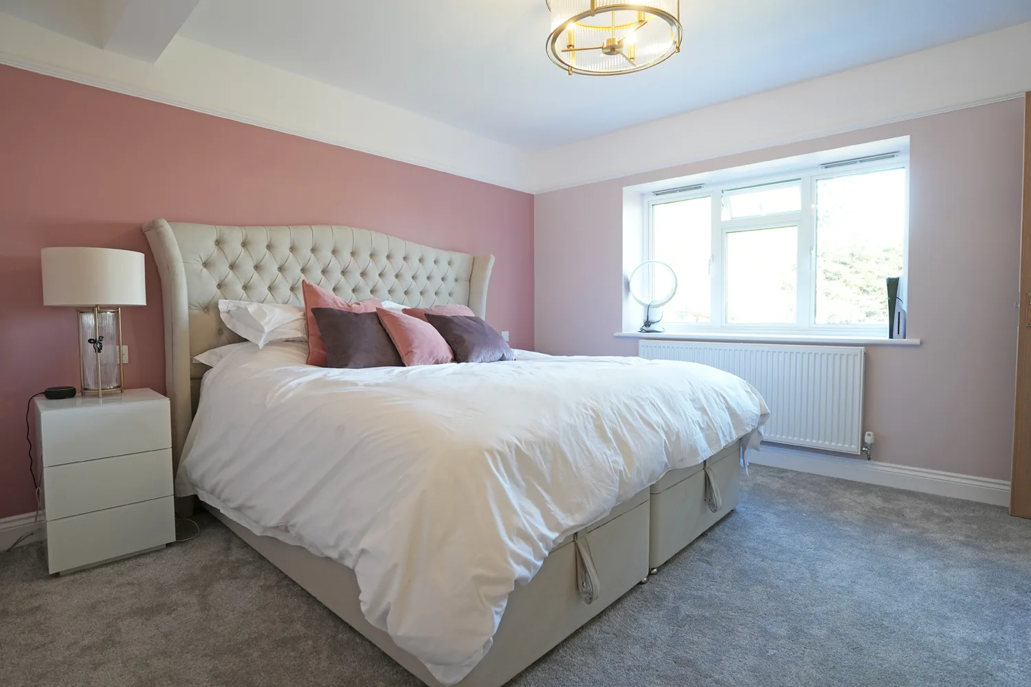 Main bedroom at the Brentwood house with buttoned headboard and brass ceiling light, part of the new full height upper floor