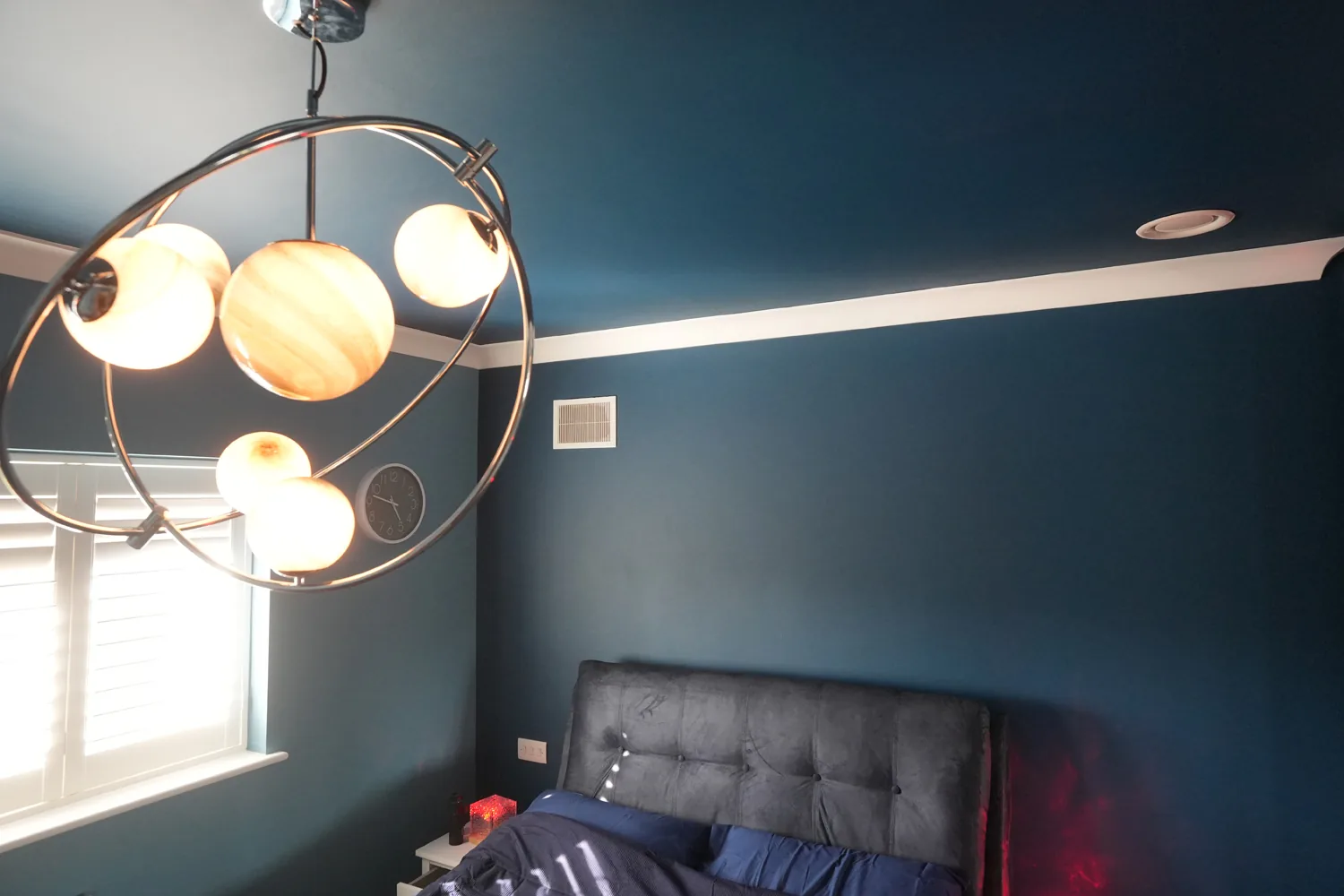 Bedroom at the Brentwood house decorated in deep teal with a globe chandelier.