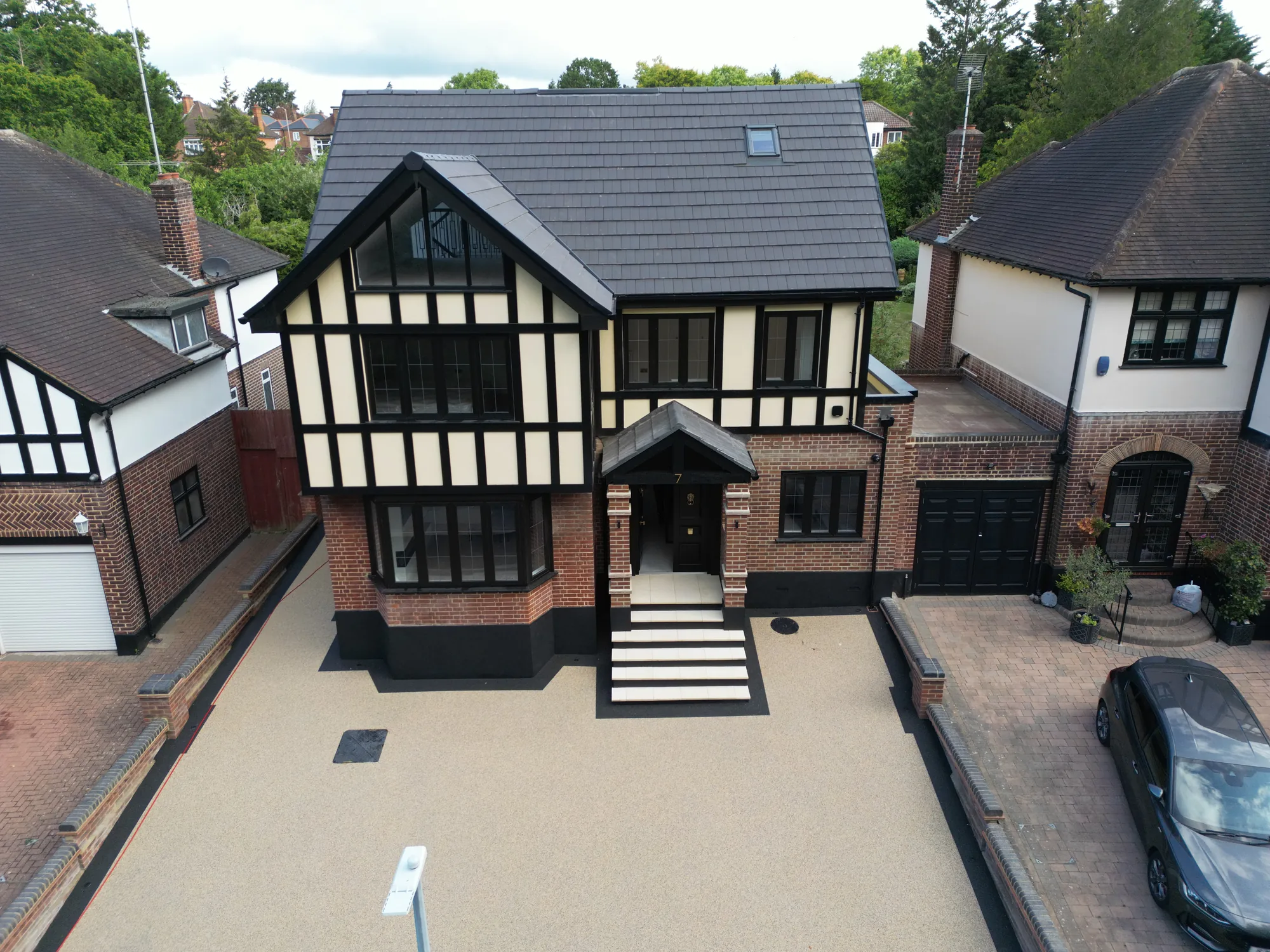 Drone view of the Chigwell whole house design and build, front elevation with timber cladding, brick detail and resin bound drive