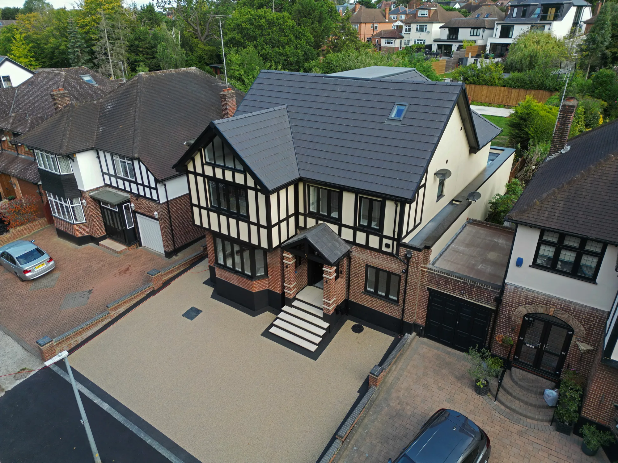 Aerial view of the completed Chigwell new build, timber clad Tudor style front elevation and resin bound driveway