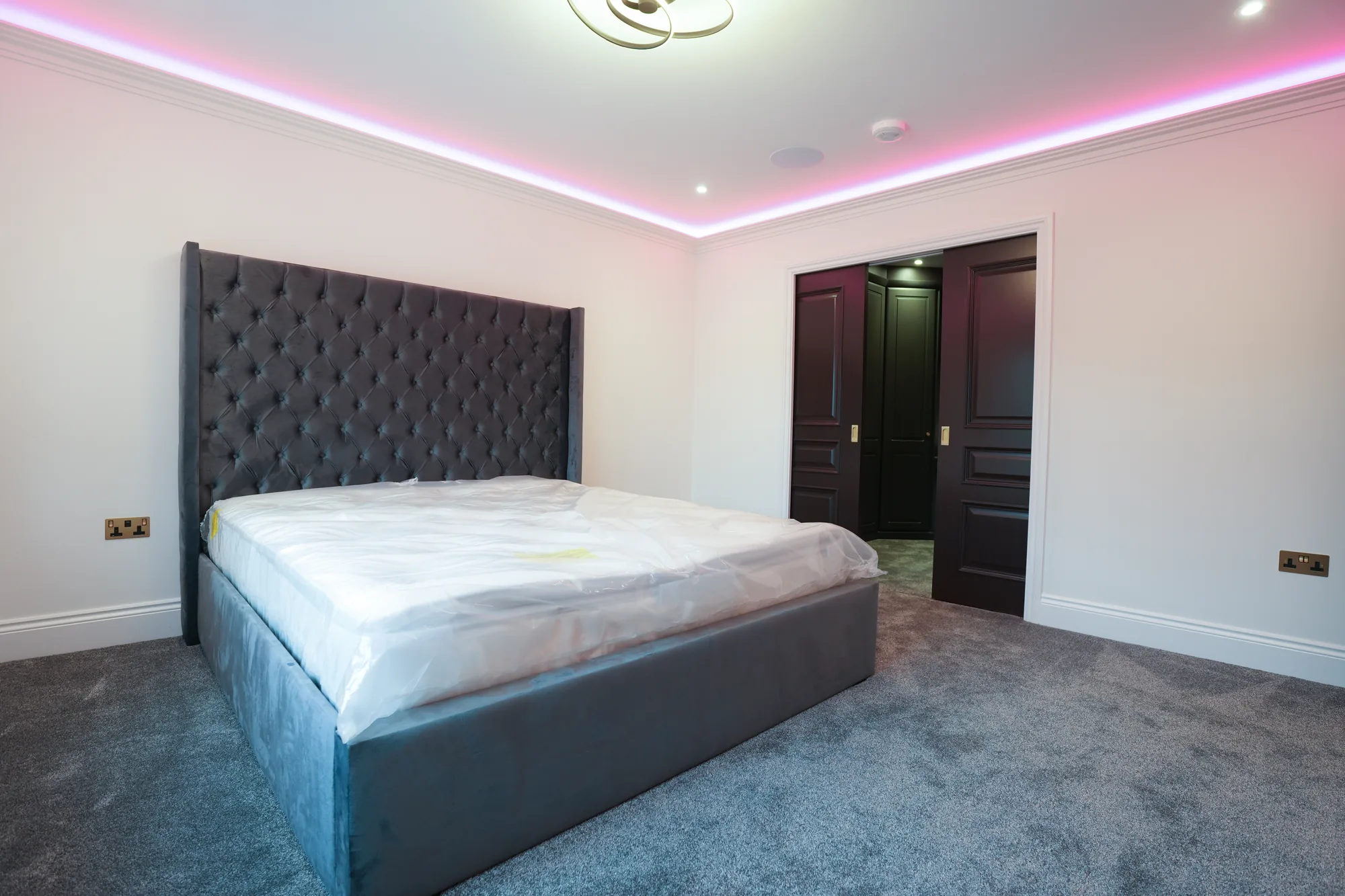 Chigwell bedroom with buttoned headboard and LED perimeter lighting.