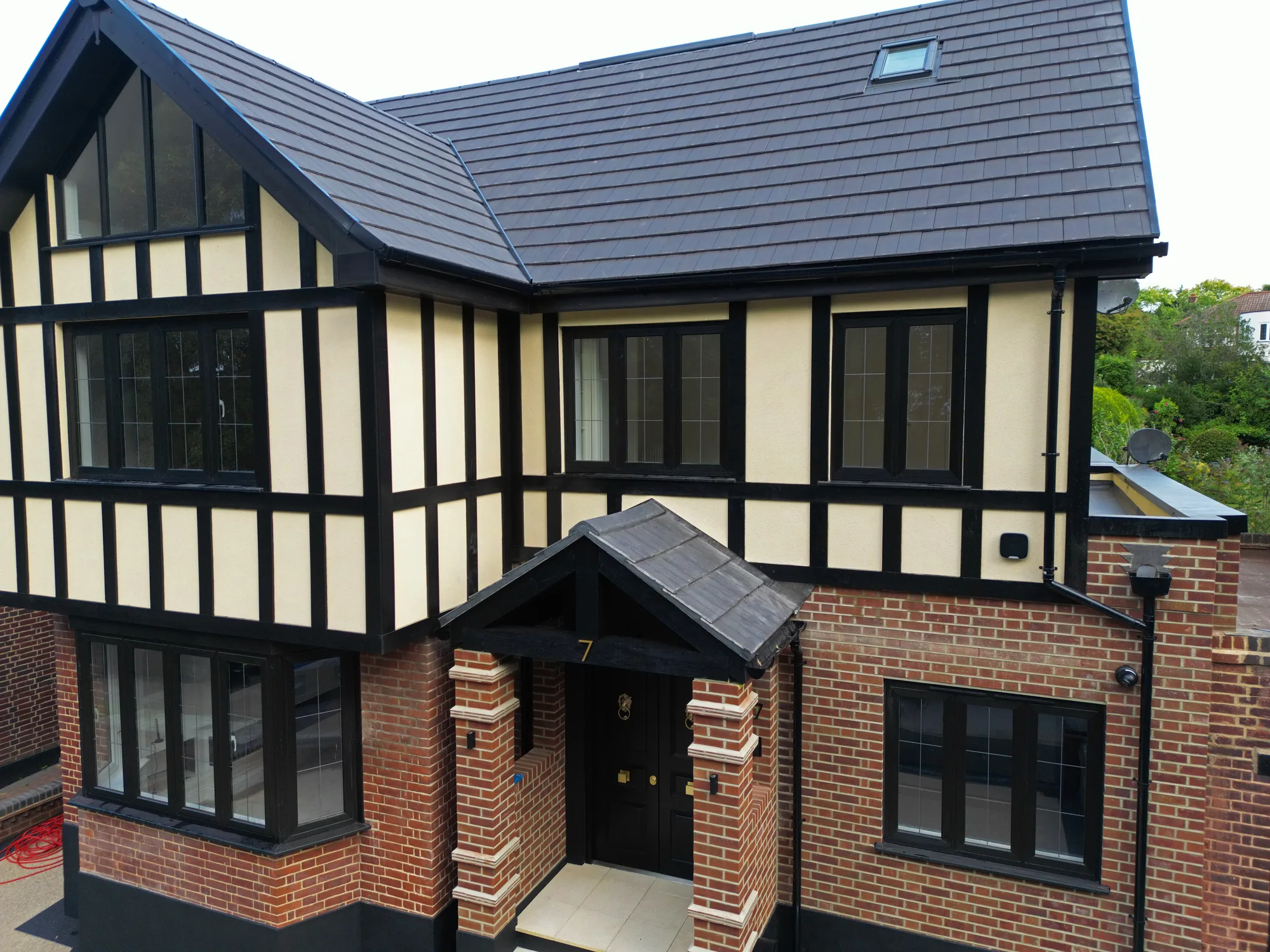 Front elevation and brick porch of the completed Chigwell new build, timber clad Tudor style detailing
