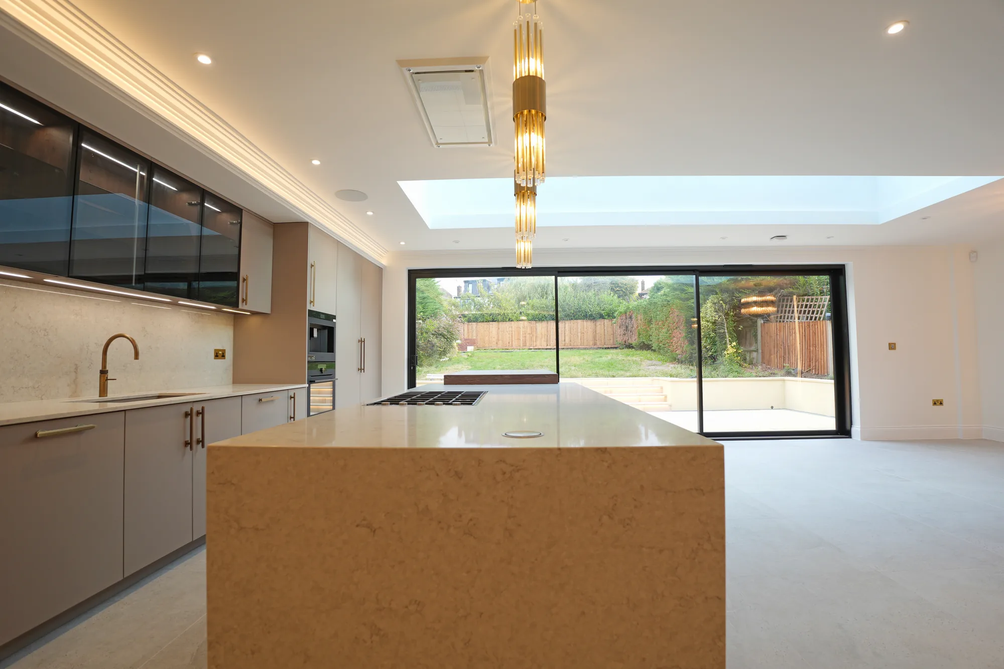 Chigwell kitchen with stone topped island and sliding doors opening to the garden.