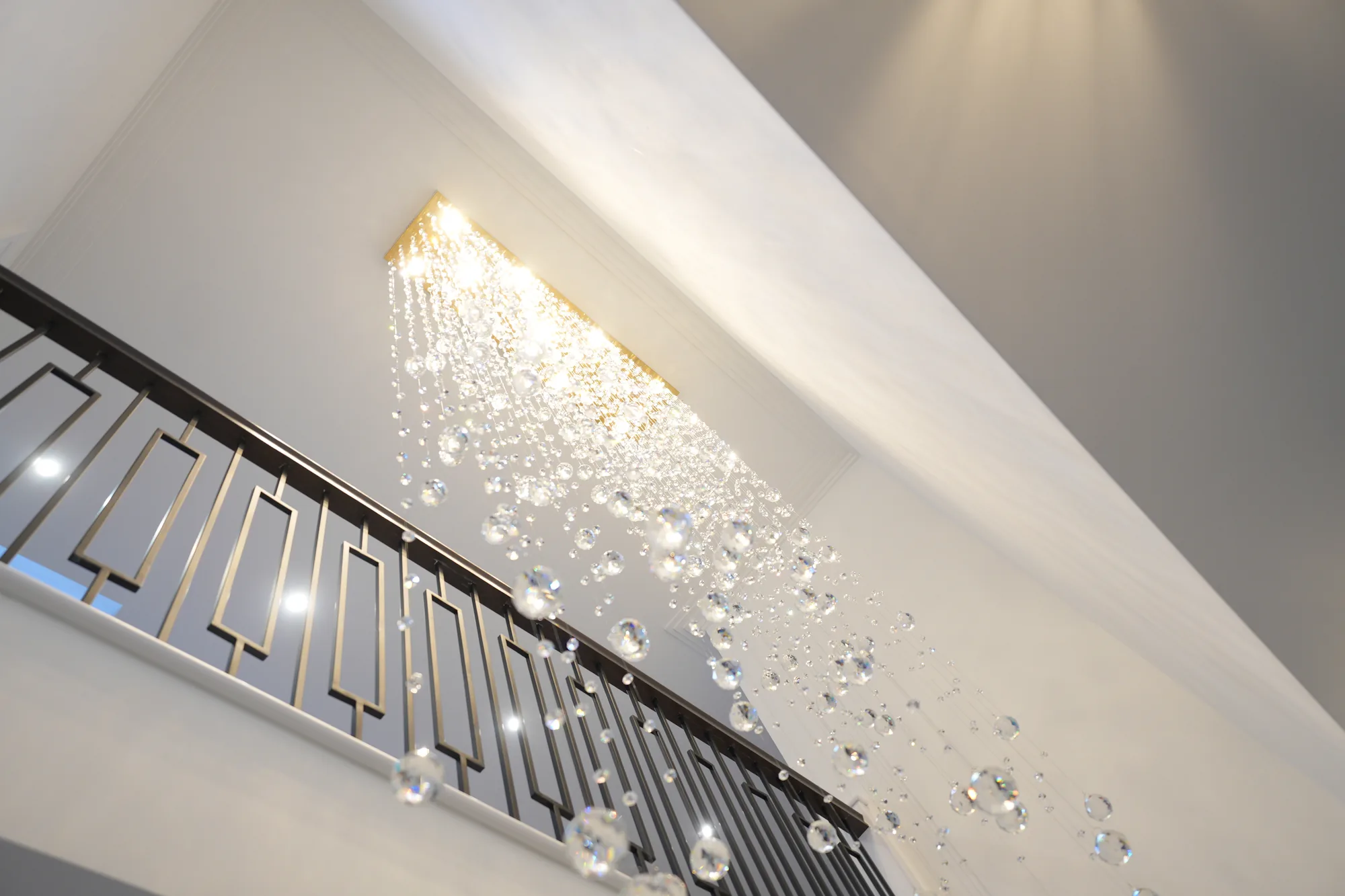 Cascading crystal chandelier over the staircase with black metal balustrade at Chigwell
