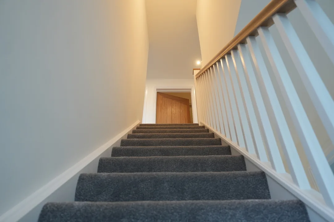 The new staircase at the Cold Norton house with white spindles and grey carpet