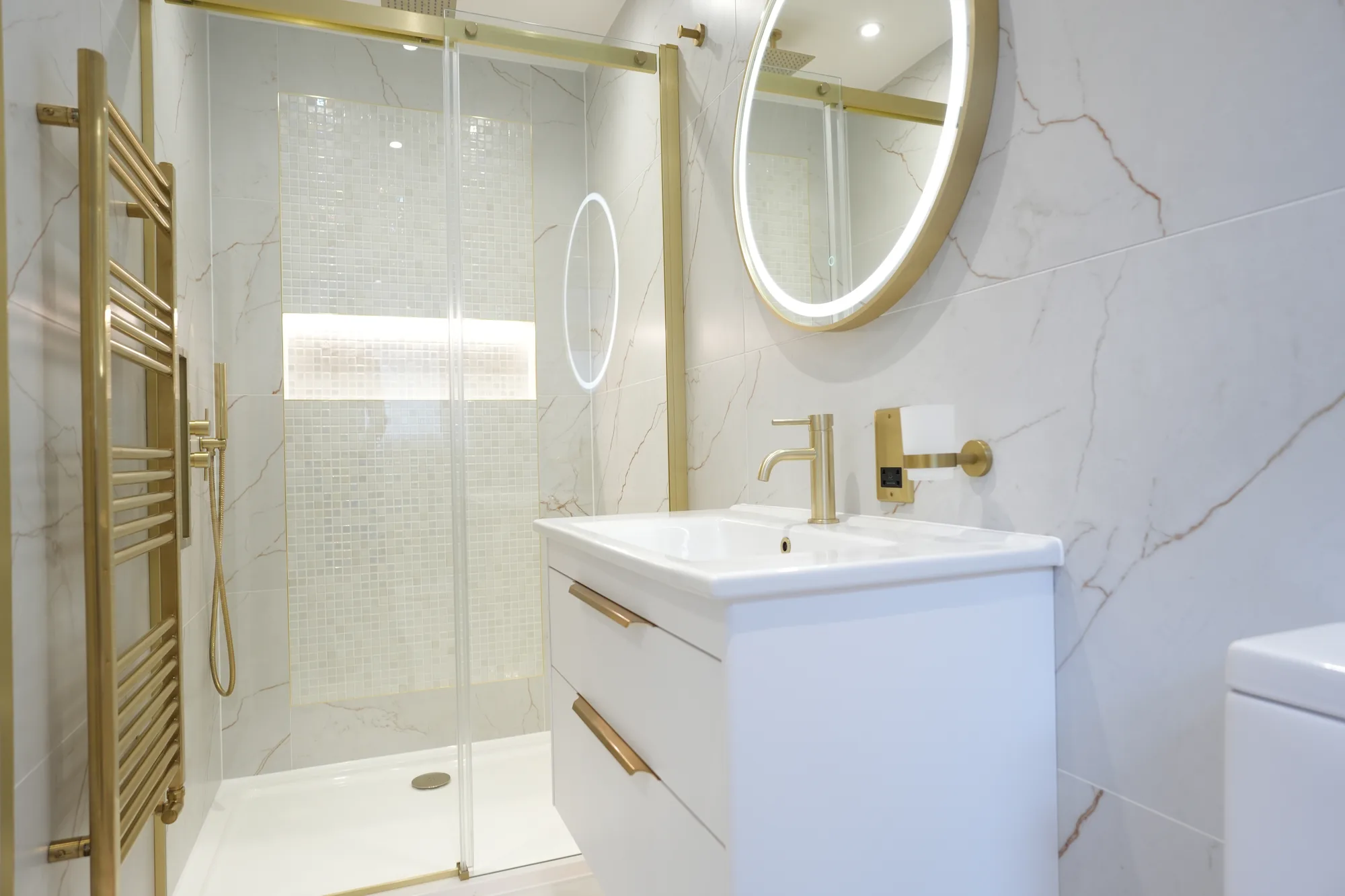 Marble shower room with brass fittings at the Chigwell project.