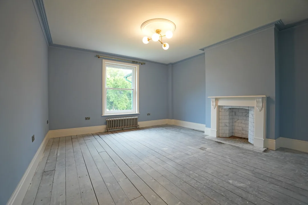 Blue room at the 1850s Wickham Bishops house with period fireplace and restored floorboards.