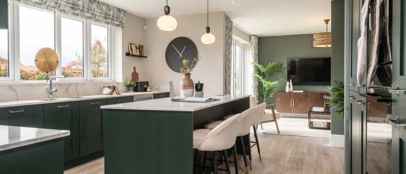 Finished show home kitchen with dark green island and pendant lights at Hendricks Green, Goffs Oak