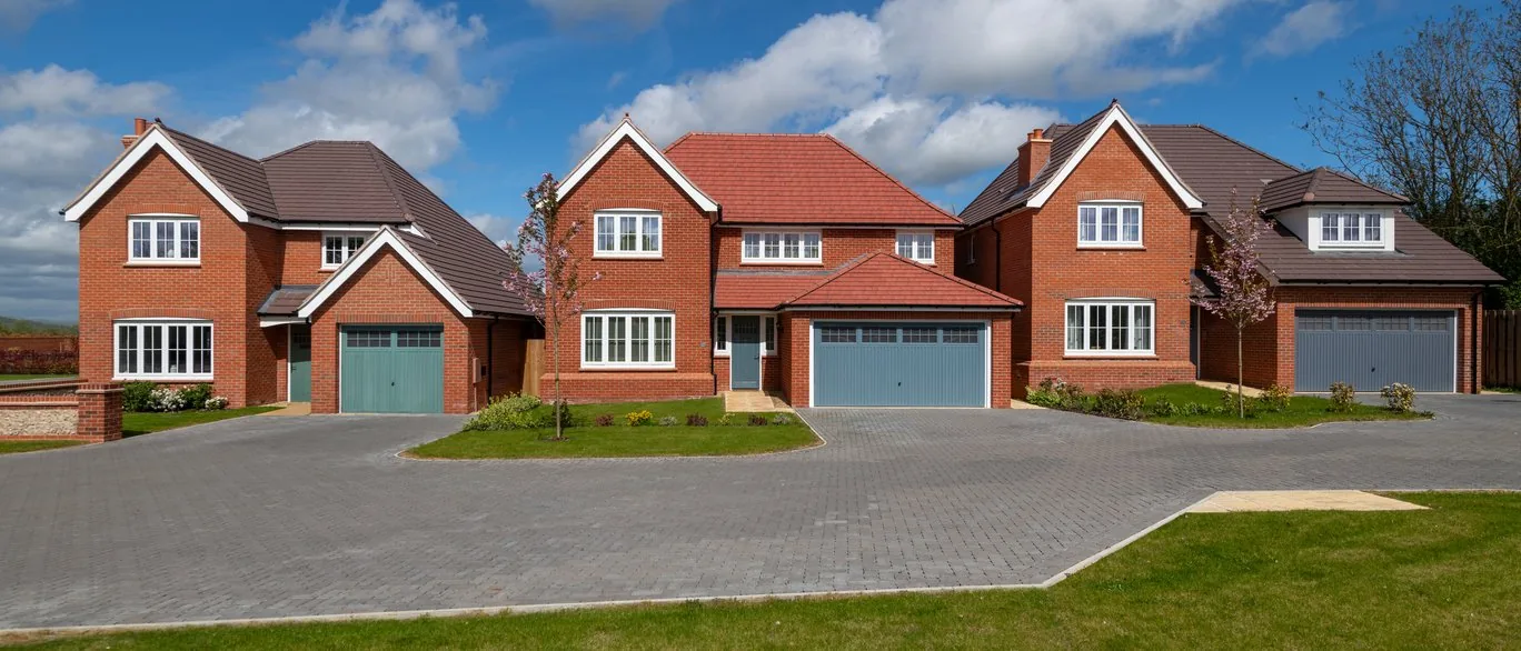Three detached red brick Redrow homes with garages at Millview Park, Bocking
