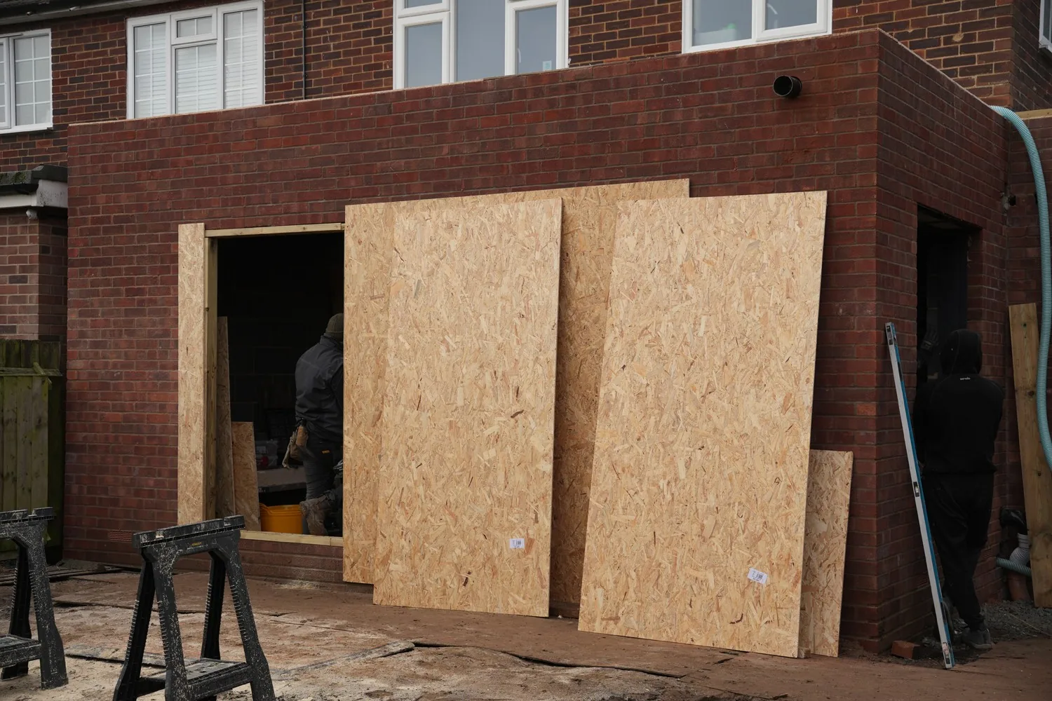 New brickwork of the Billericay side and rear extension mid-build, with OSB boards stacked against the wall ready for the roof.