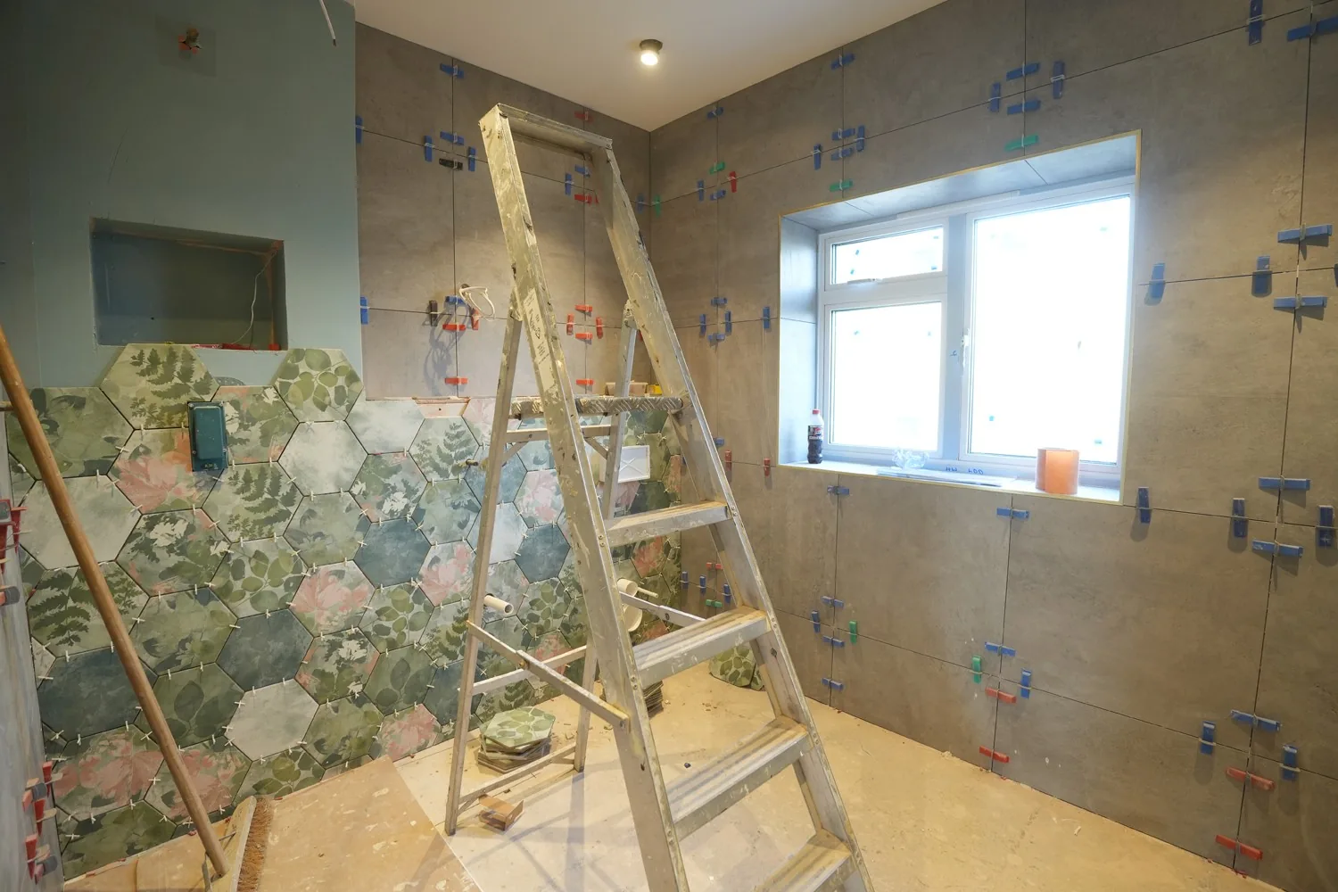 Brentwood bathroom mid tiling: botanical hexagon feature tiles on one wall, large format grey tiles with spacers on the others.