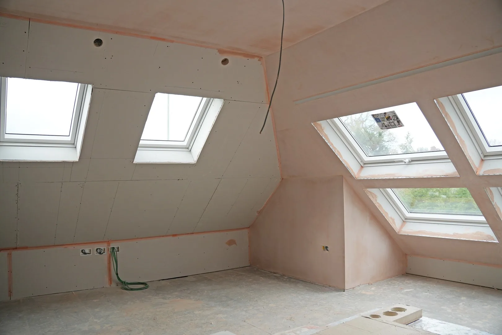 A loft room at Chigwell freshly plastered, with its banks of skylights letting the light in.