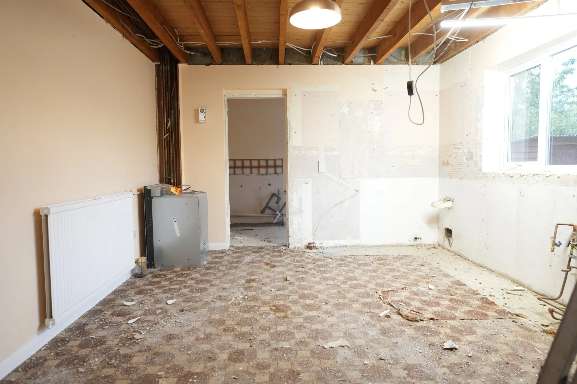 The old Cold Norton kitchen with its patterned floor tiles and part-stripped walls, the ceiling already opened above it.