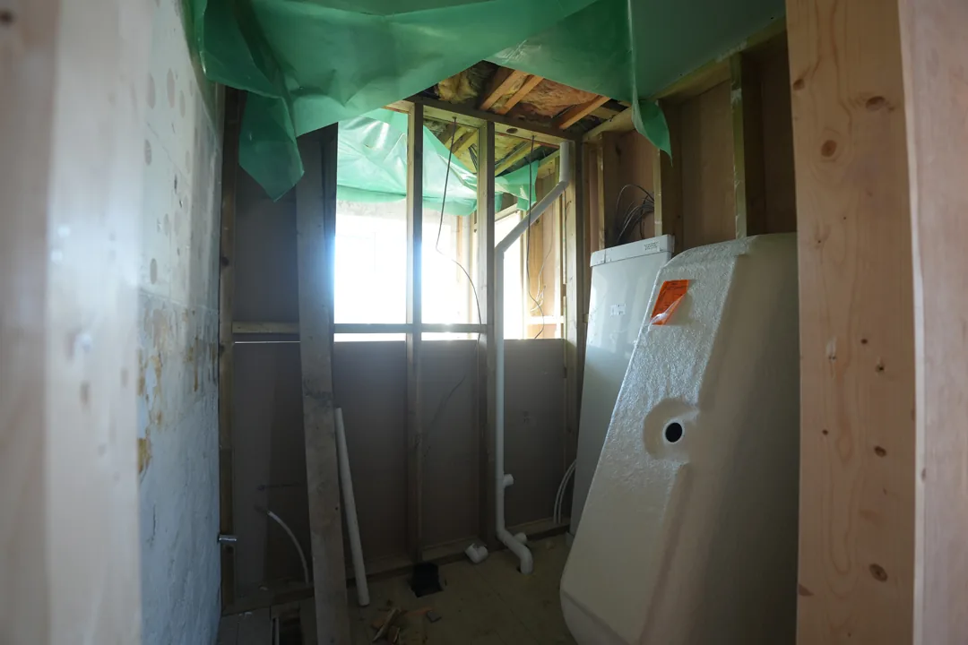 A new bathroom at first fix: stud walls, membrane and pipework in place, the shower tray waiting to go in.