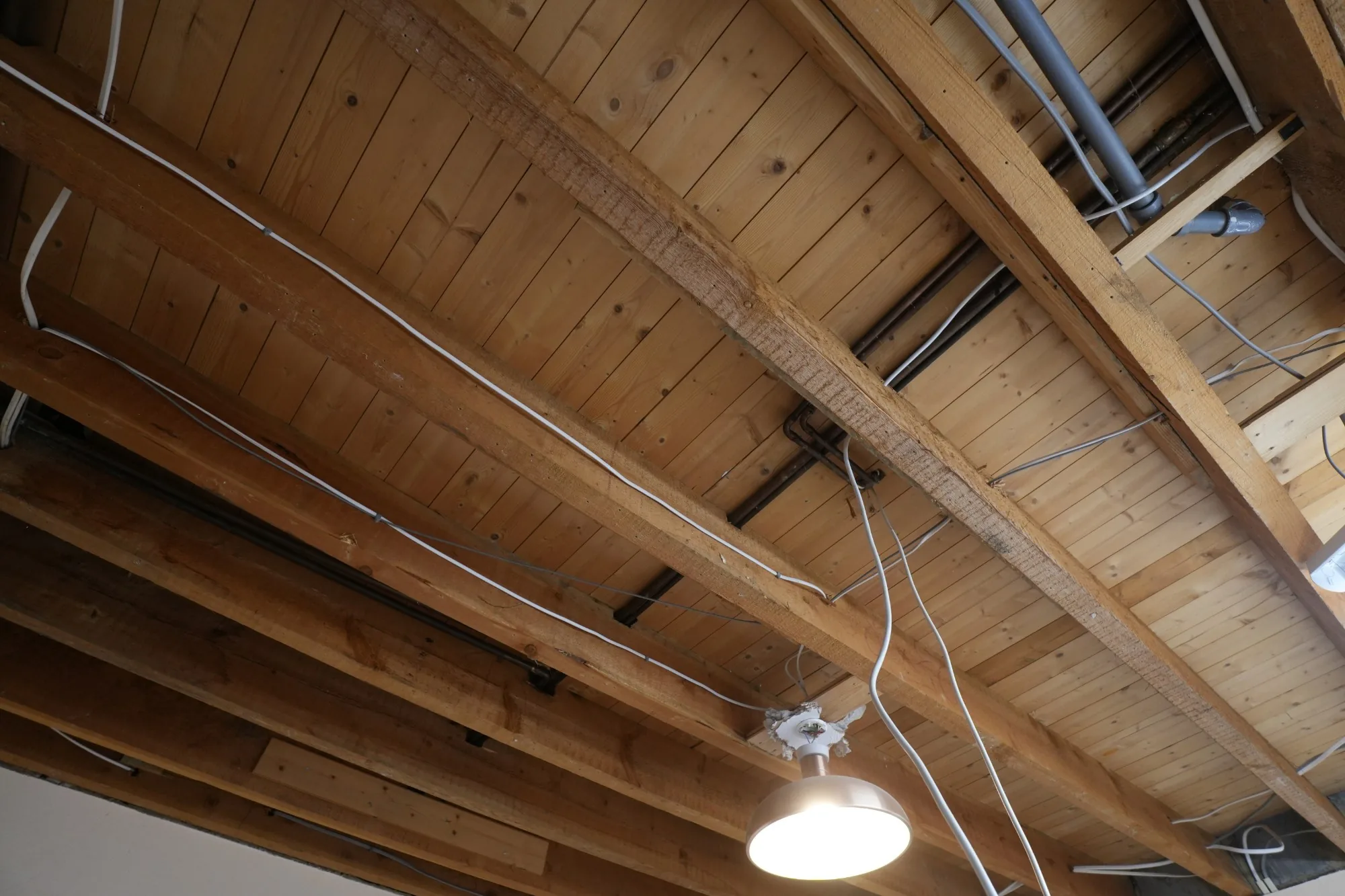 A ceiling at Cold Norton opened back to its joists, the old pipework and wiring exposed for renewal.