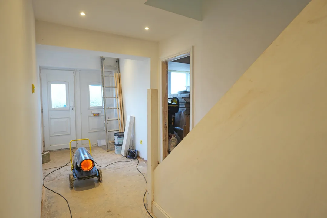 The entrance hall taking shape: the new staircase wall skimmed, materials by the front door and the heater drying the fresh work.