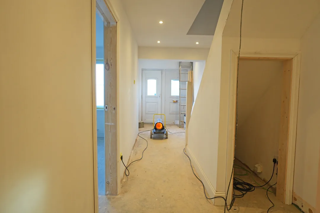 The hallway plastered, painted and lit, downlights in and a drying heater running as decoration starts.