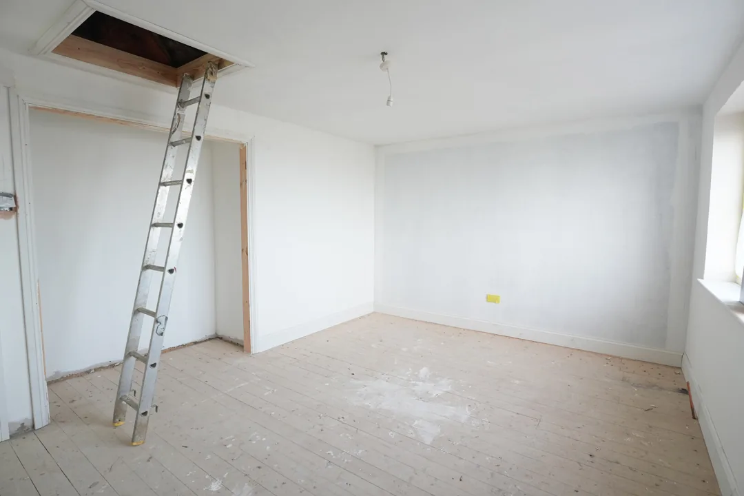A reskimmed and painted bedroom, the loft ladder down from the newly lined hatch.