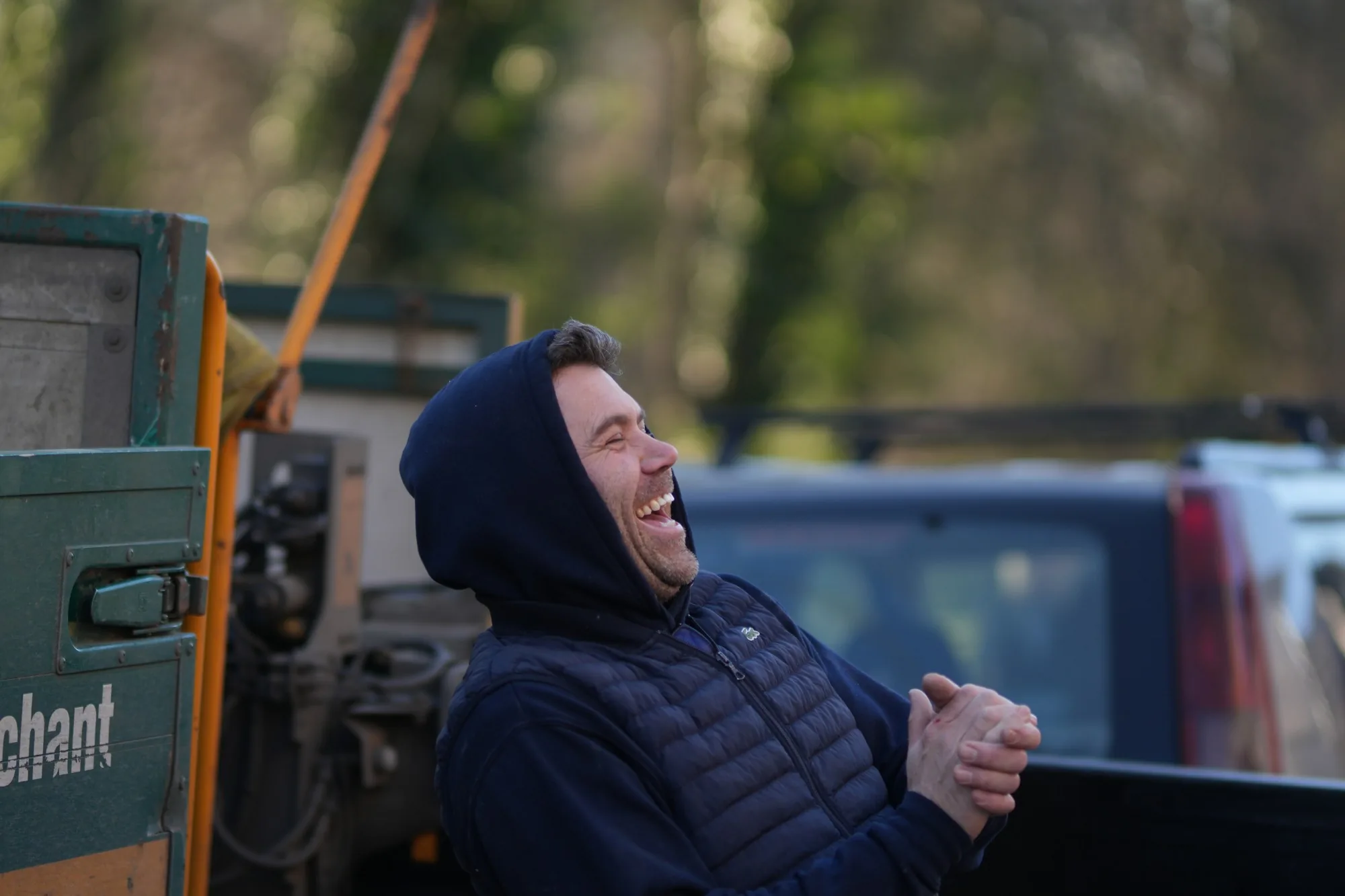 Craig Bellamy sharing a laugh on site, plant machinery and vans behind him