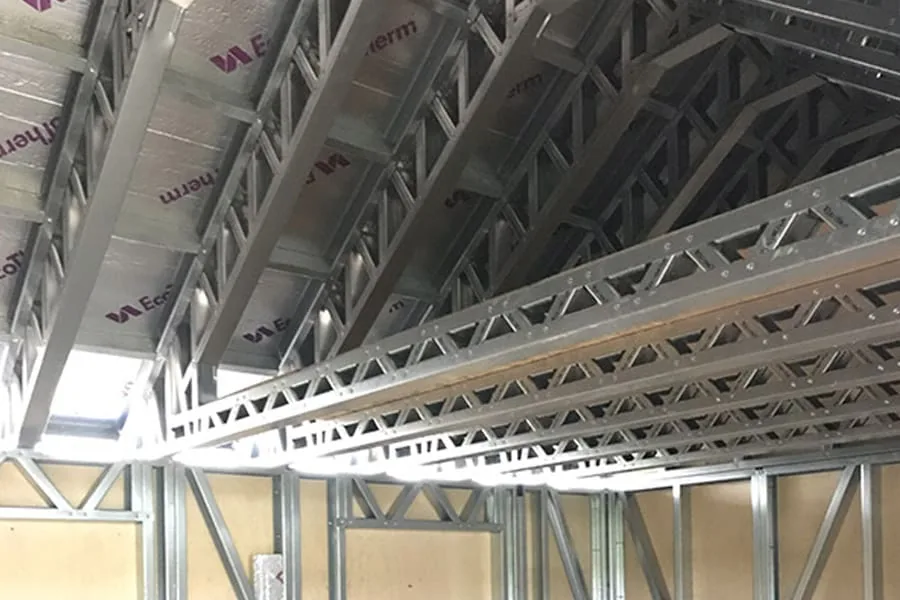 Light gauge steel roof trusses inside a steel frame building, with insulation boards fitted between the joists.