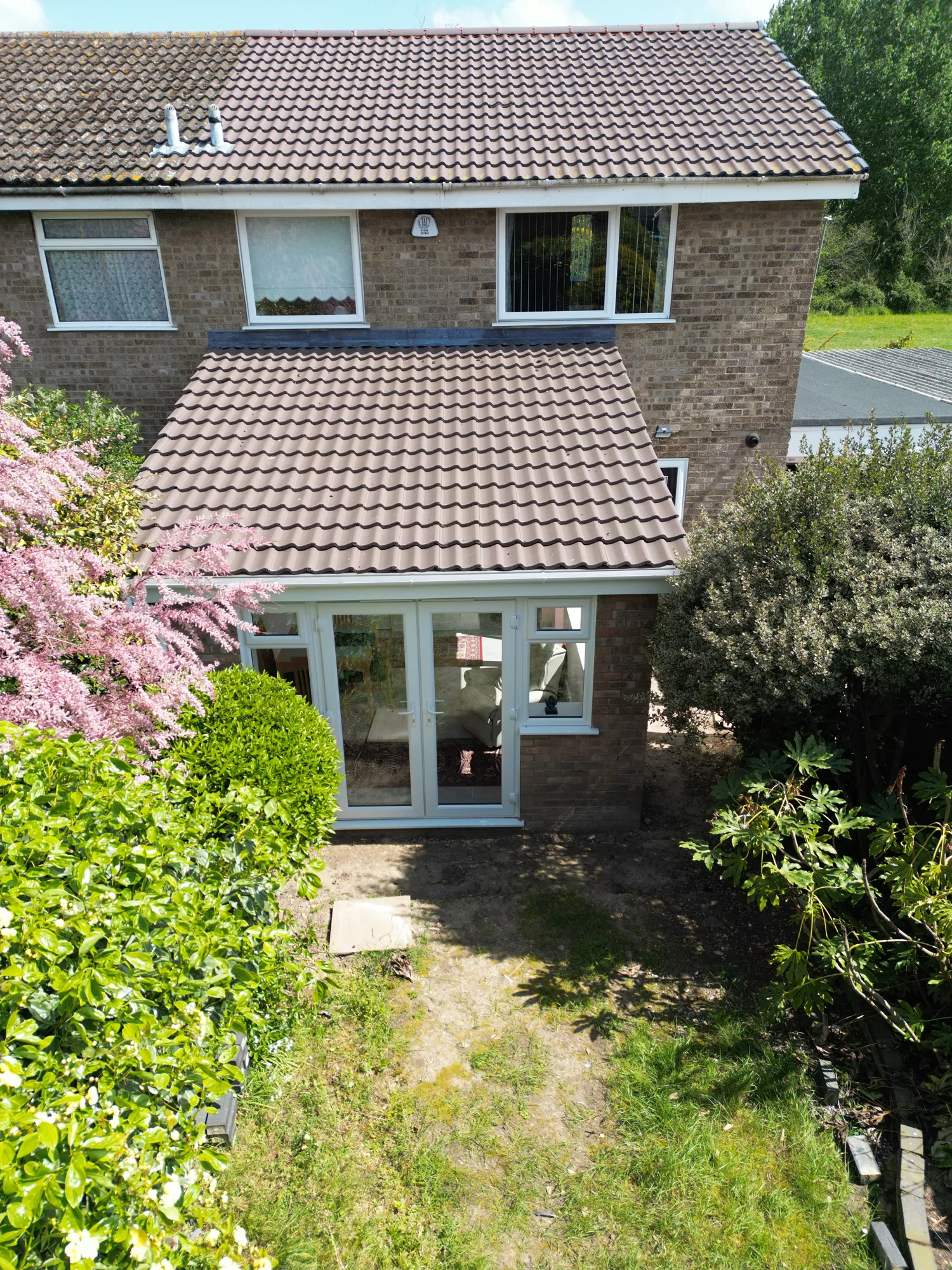 A closer drone view of the Witham extension's tiled pitched roof and French doors from the garden side.